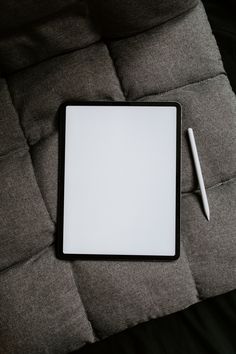 a tablet with a pen on top of it next to a white paper and a pencil