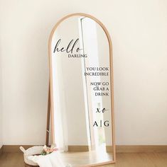 a mirror sitting on top of a wooden floor next to a vase with flowers in it