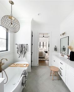 a bathroom with white walls and gray flooring next to a bathtub in the corner