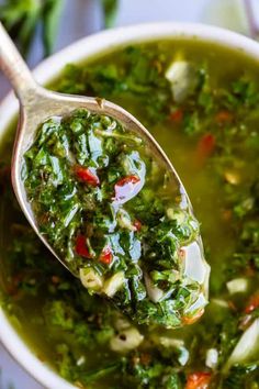 a spoon full of green vegetable soup on top of a table