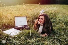 a woman laying in the grass next to an old record player with her hand on her chin