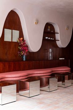 a room that has some benches and mirrors on the wall with flowers in vases