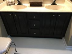 a bathroom with double sinks and black cabinets