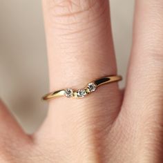 a woman's hand wearing a gold ring with three small diamonds on the band