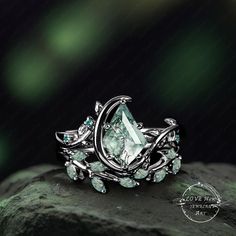 a green ring sitting on top of a rock with leaves and stones in the middle