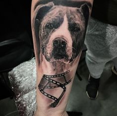 a man with a dog tattoo on his arm is holding a film strip and looking at the camera