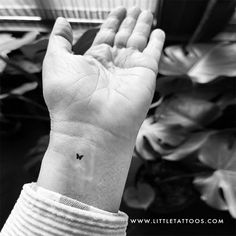 a black and white photo of a butterfly tattoo on the left wrist by little tattoos