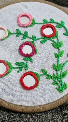 a close up of a embroidery on a piece of cloth with flowers in the middle