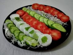 sliced cucumbers, tomatoes and onions on a black plate