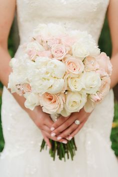 a bride holding a bouquet of white and pink flowers