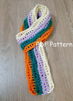 a multicolored crocheted scarf laying on top of a wooden floor