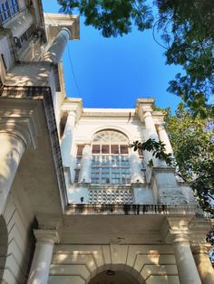 an old building with columns and windows on the front, looking up at the sky