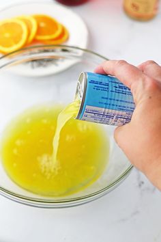 someone is pouring orange juice into a glass bowl