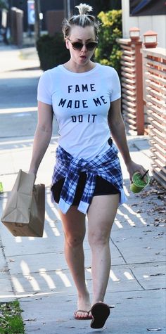 a woman walking down the street carrying shopping bags and a paper bag in her hand