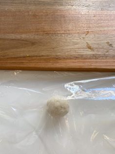 a ball of wool sitting on top of a plastic bag next to a wooden board