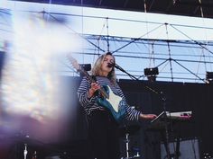 a woman playing guitar on stage at an outdoor concert