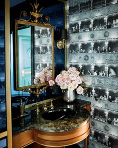 a bathroom with a sink, mirror and flowers on the counter