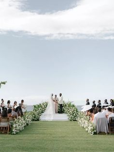 an outdoor wedding ceremony with white flowers and greenery on the aisle, overlooking the ocean