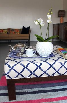 a coffee table with a potted plant and tea set on it in front of a couch