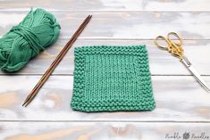 a green crochet square next to a pair of scissors and yarn