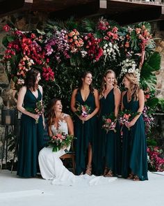 a group of women standing next to each other in front of a flower covered wall