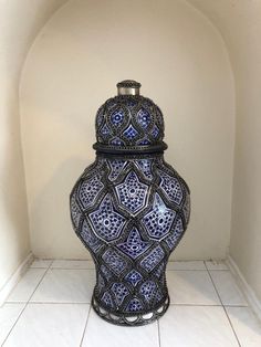 a blue and white vase sitting on top of a tile floor next to a wall