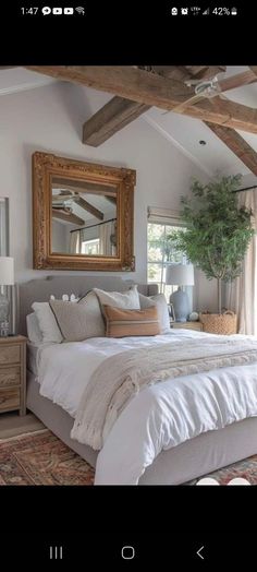 a large bed sitting under a wooden beam in a bedroom next to a window with curtains