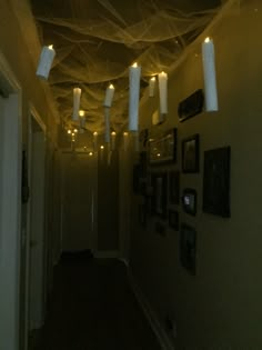 a hallway with lights hanging from the ceiling and some pictures on the wall behind it