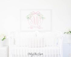 a white crib with flowers and a framed monogrammed print on the wall