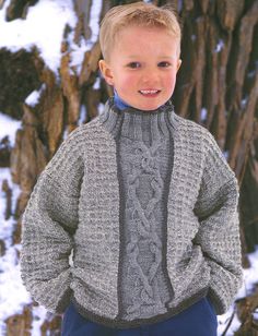 a young boy standing in the snow wearing a sweater