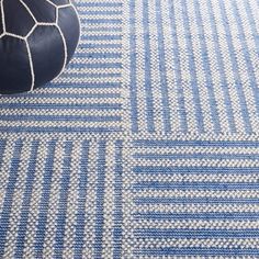 a blue and white rug on the floor with a black ball sitting next to it