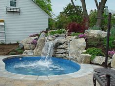 a backyard with a pool and waterfall in the middle