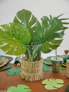 there is a plant in a vase on the table with plates and cups around it