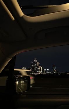 the view from inside a car at night with city lights in the backgroud