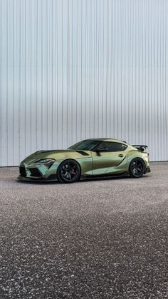 a green sports car is parked in front of a white building with vertical striped walls