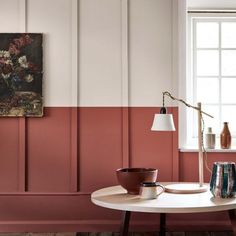 a living room with pink and white walls, coffee table, vases and lamp