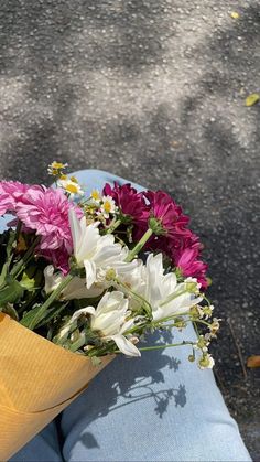 a bouquet of flowers sitting on top of a person's lap in the street