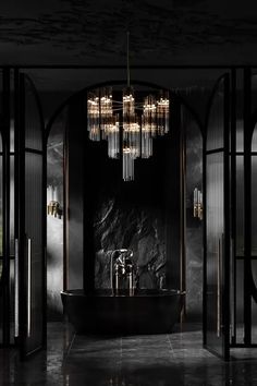 a black and white bathroom with chandelier above the bathtub in front of it