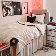 a bed with white sheets and black pillows in a bedroom next to pictures on the wall