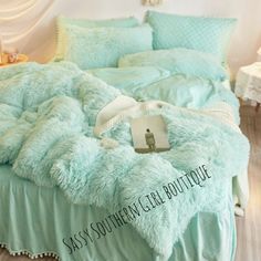 a bed covered in blue fluffy blankets and pillows