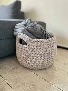 a gray couch with a basket on the floor next to it and some clothes in it