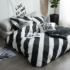 black and white striped bedding in a bedroom with plants on the wall behind it