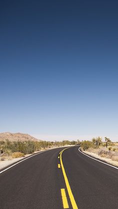 an empty road in the desert with no cars or people on it, under a clear blue sky