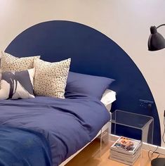 a bed with blue sheets and pillows on top of it next to a night stand