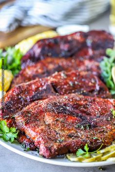 some meat and vegetables on a plate with lemon wedges next to it, along with a glass of beer