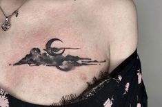 a woman with a tattoo on her chest is wearing a black top and has clouds in the sky