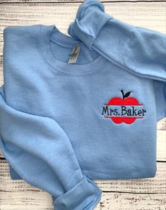 Teacher Sweatshirt-Teacher Shirts-Teach Sweatshirt-Custom Embroidered Sweatshirt-Teacher Gifts-Custom Sweatshirt This custom embroidered sweatshirt is super soft, unisex in size and makes a trendy sweatshirt to wear with pride! Any teacher will be able to wear this for many school years to come! With so many sweatshirt colors to choose from, treat yourself or your favorite teacher to more than one! Apple design will be embroidered in Red thread, with Black thread for stem and leaf as shown on th School Sweatshirt With Embroidered Logo, Hand Embroidered Teacher Shirt, Preschool Teacher Sweatshirt, Embroidered Teacher Sweatshirt, Teach Sweatshirt, Teacher Appreciation Crew Neck T-shirt For Back To School, Custom Embroidered Sweatshirt, Navy Sweatshirt, Sweatshirt Colors