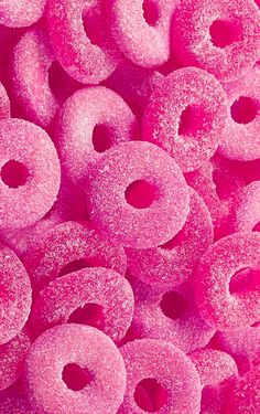 a pile of pink donuts with sprinkles on them