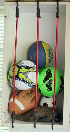 several sports balls are stacked on top of each other in a storage unit with red handles