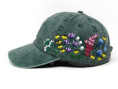 a green hat with colorful flowers embroidered on the front and side, sitting against a white background